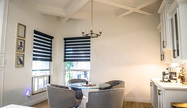 dining space with beamed ceiling, coffered ceiling, and light hardwood / wood-style floors