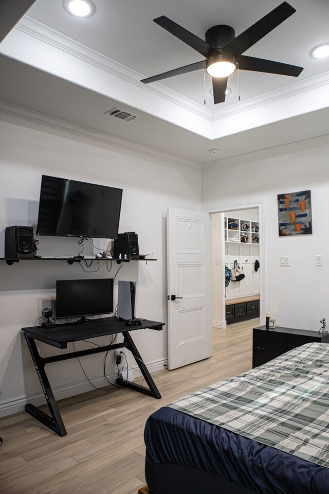 bedroom with crown molding, ceiling fan, a tray ceiling, and light hardwood / wood-style flooring