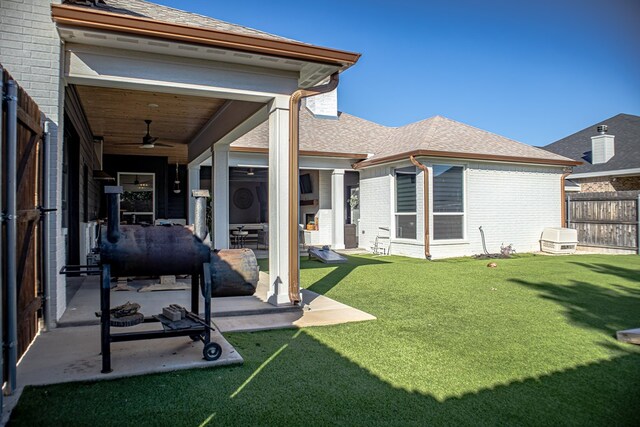 back of property with a yard, a patio area, and ceiling fan