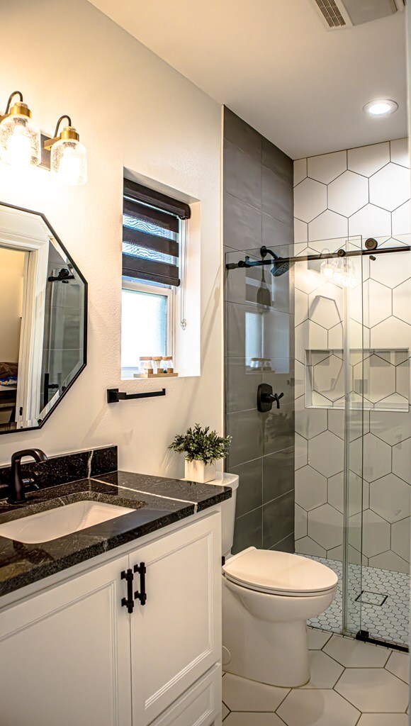 bathroom with vanity, tile patterned flooring, toilet, and walk in shower