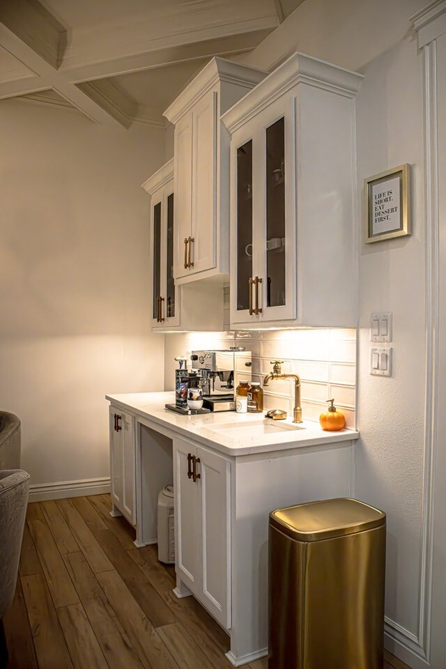 bar featuring dark wood-type flooring, sink, white cabinetry, beamed ceiling, and backsplash