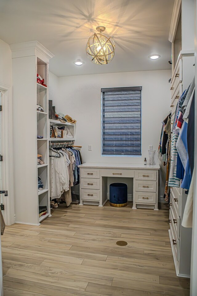 spacious closet featuring a notable chandelier and light hardwood / wood-style floors