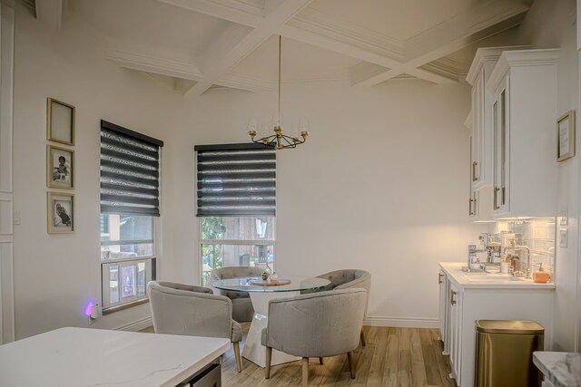 dining room with coffered ceiling, sink, light hardwood / wood-style flooring, and beamed ceiling