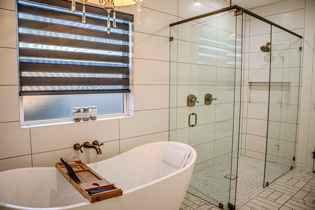 bathroom featuring shower with separate bathtub and tile walls