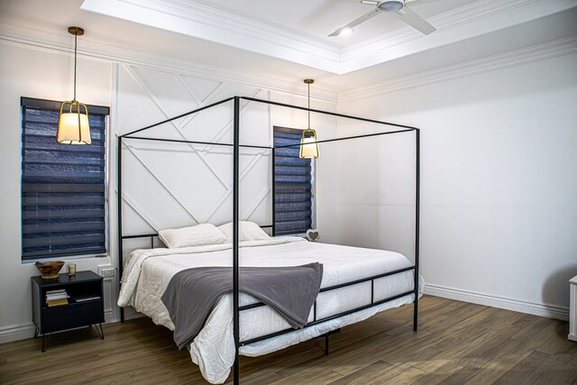 bedroom featuring a raised ceiling, crown molding, and dark wood-type flooring