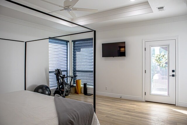 bedroom featuring crown molding, access to exterior, a raised ceiling, and light hardwood / wood-style floors