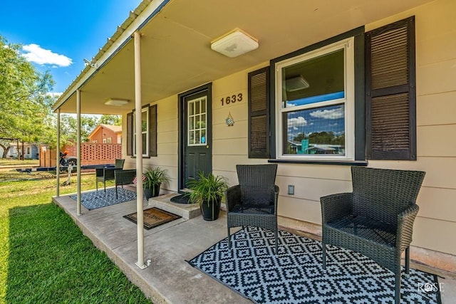 view of exterior entry with a porch and a lawn