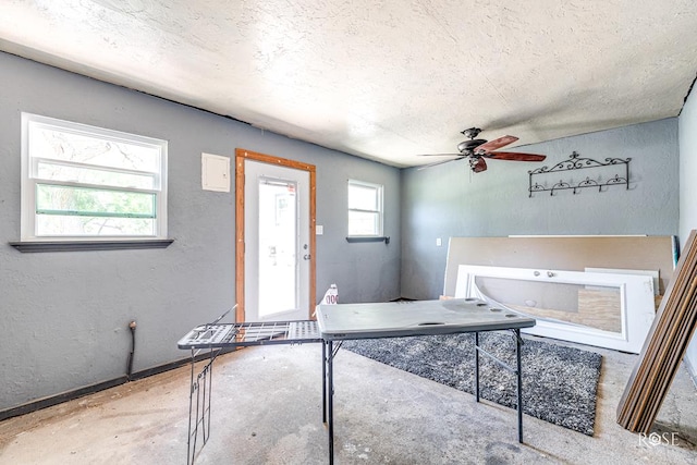 interior space featuring unfinished concrete flooring, a ceiling fan, and a textured ceiling