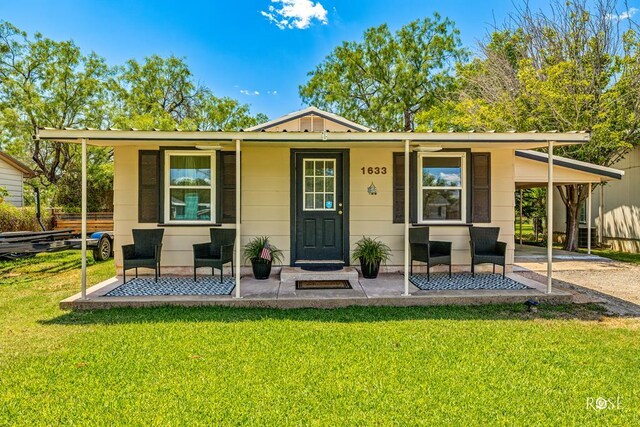 view of front facade featuring a front lawn, covered porch, and an attached carport