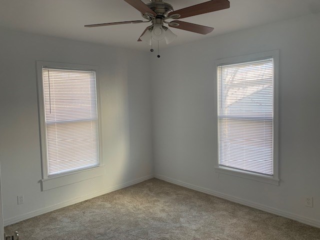 carpeted empty room featuring ceiling fan