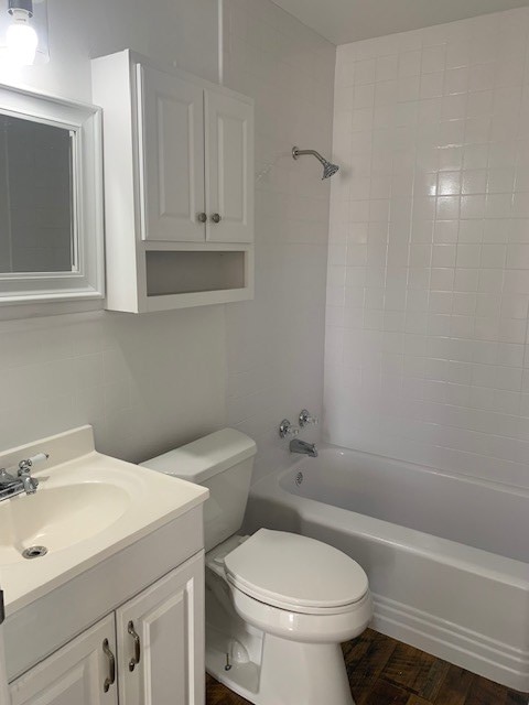 full bathroom with vanity, hardwood / wood-style floors, tiled shower / bath combo, and toilet