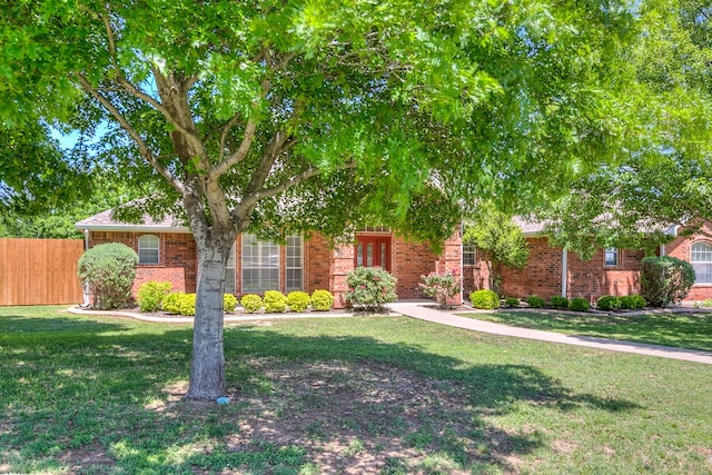 obstructed view of property with a front lawn, brick siding, and fence