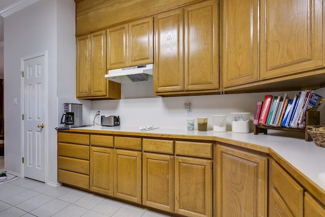 kitchen with brown cabinetry, light tile patterned floors, under cabinet range hood, and light countertops