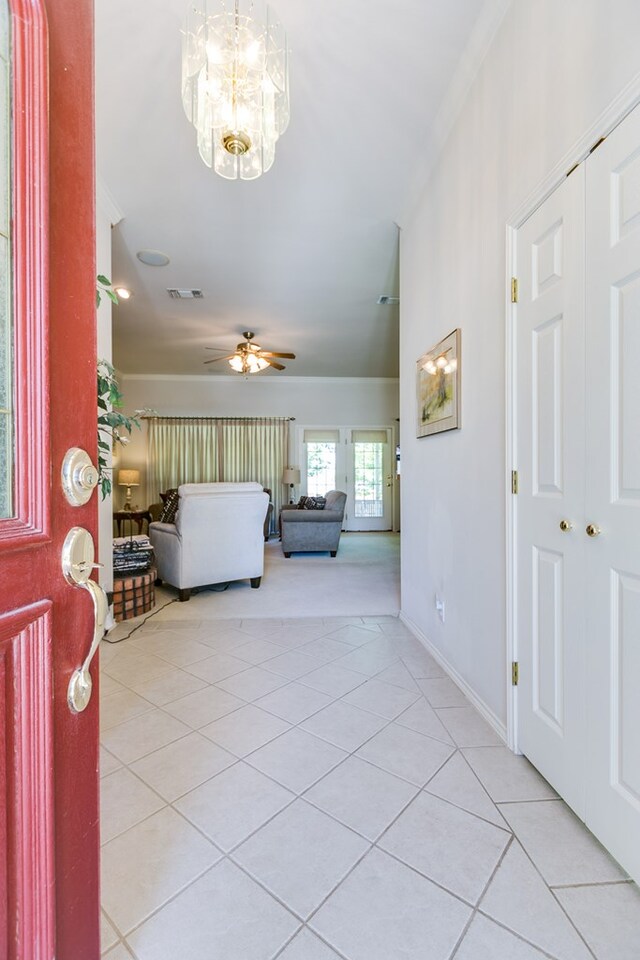 foyer entrance featuring light tile patterned floors, baseboards, radiator, ornamental molding, and ceiling fan with notable chandelier