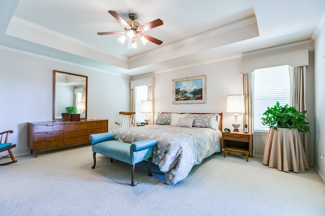 bedroom with carpet flooring, a tray ceiling, crown molding, a ceiling fan, and baseboards
