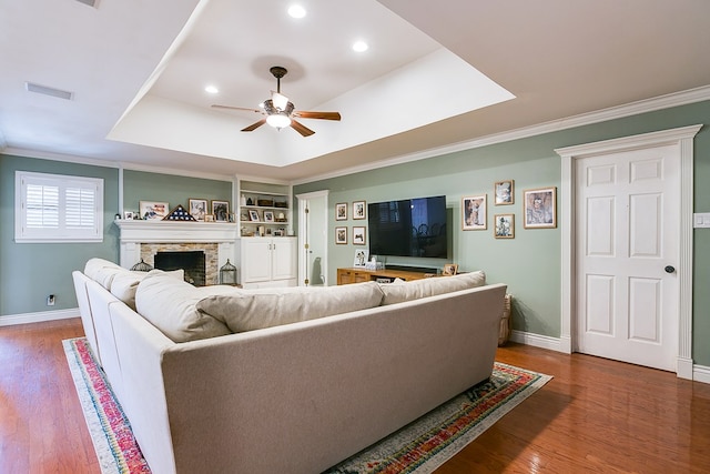 living room featuring a raised ceiling, dark hardwood / wood-style floors, built in features, and ceiling fan