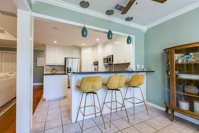 kitchen with appliances with stainless steel finishes, white cabinetry, backsplash, ornamental molding, and kitchen peninsula