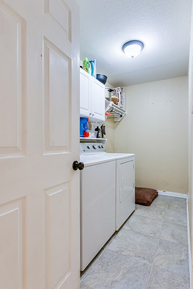 washroom with washer and dryer, cabinets, and a textured ceiling