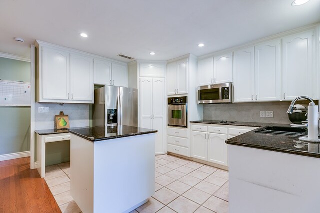 kitchen with appliances with stainless steel finishes, sink, dark stone countertops, decorative backsplash, and a center island