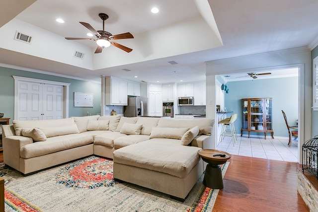 living room featuring a high ceiling, crown molding, ceiling fan, and light hardwood / wood-style floors