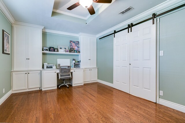 unfurnished office with crown molding, ceiling fan, wood-type flooring, and a barn door