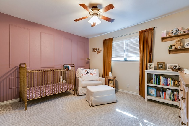 carpeted bedroom with a nursery area and ceiling fan