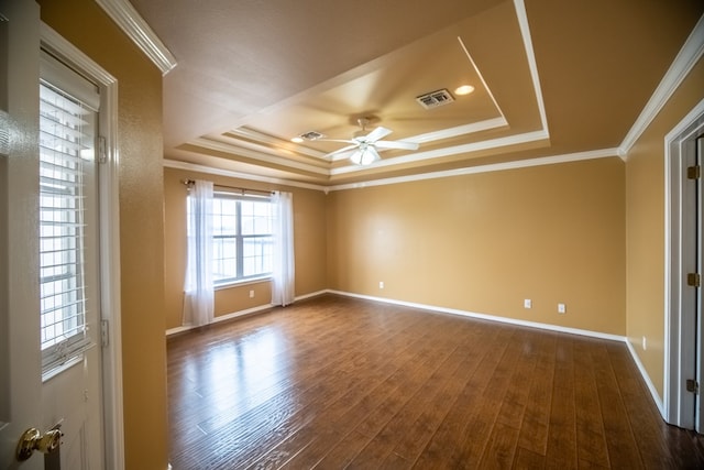 unfurnished room with ornamental molding, a tray ceiling, dark wood-type flooring, and visible vents