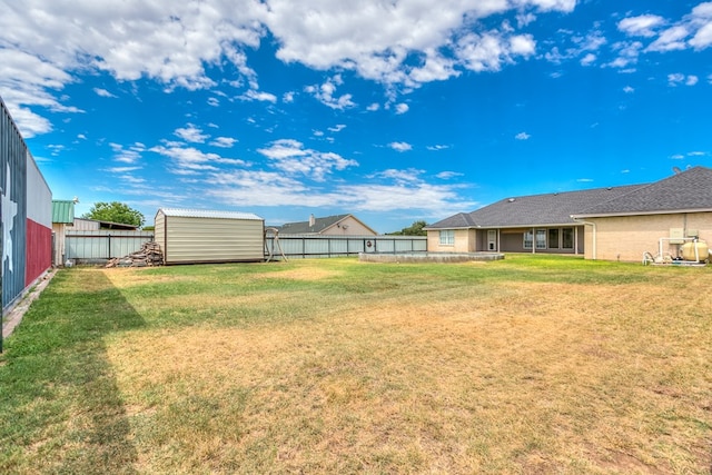 view of yard featuring a storage shed, a fenced backyard, and an outdoor structure