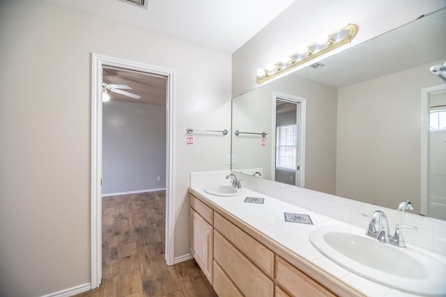 full bath with wood finished floors, a sink, baseboards, and double vanity