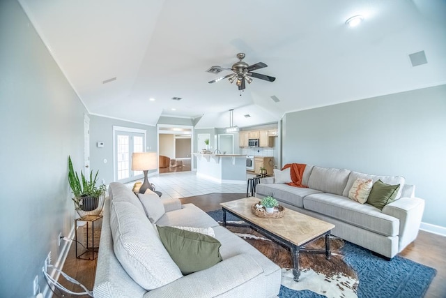 living room with lofted ceiling, ornamental molding, light wood-style floors, ceiling fan, and baseboards