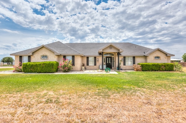 ranch-style home featuring a shingled roof, brick siding, and a front lawn