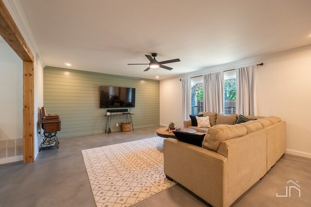 living room featuring wooden walls, ornamental molding, and ceiling fan