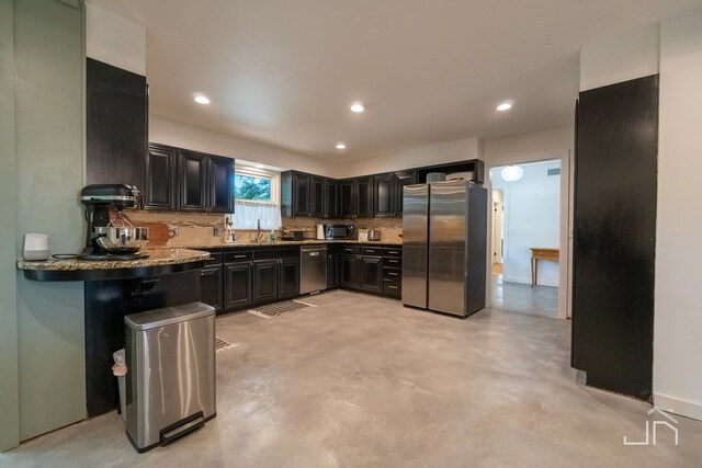 kitchen with tasteful backsplash, sink, light stone countertops, and appliances with stainless steel finishes