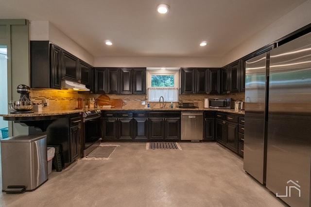 kitchen with appliances with stainless steel finishes, stone countertops, sink, and backsplash