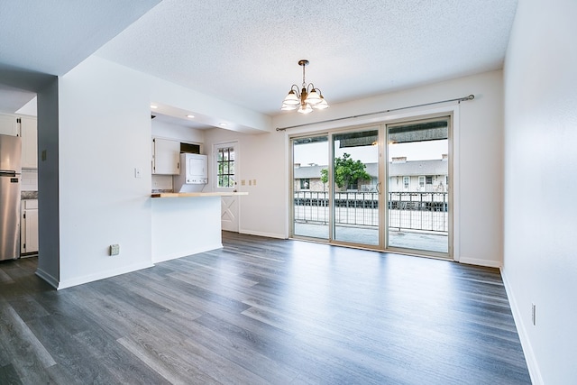 2472-D University Ave, San Angelo, TX 76904 - unfurnished living room with a chandelier, dark wood finished floors, baseboards, and a textured ceiling