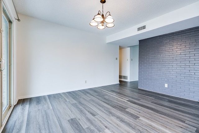 2472-D University Ave, San Angelo, TX 76904 - unfurnished room with brick wall, wood finished floors, a chandelier, and baseboards