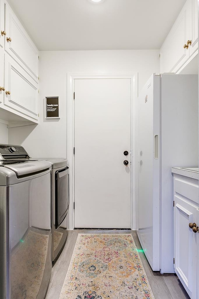 2671 Oxford Ave, San Angelo, TX 76904 - clothes washing area featuring cabinet space, washer and clothes dryer, and light wood-style floors