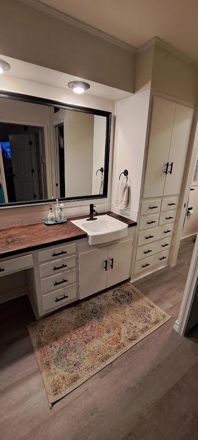 bathroom featuring crown molding, wood finished floors, and vanity