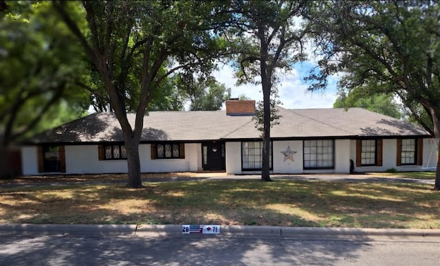 ranch-style house featuring a chimney and a front yard