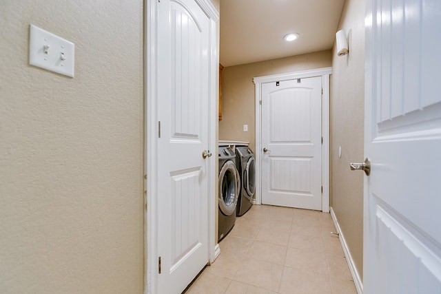 laundry room with light tile patterned floors, a textured wall, washing machine and dryer, laundry area, and baseboards