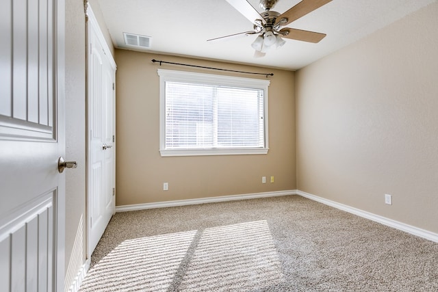 carpeted empty room featuring a ceiling fan, visible vents, and baseboards