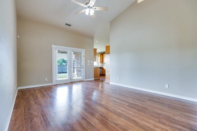 unfurnished living room featuring visible vents, a high ceiling, a ceiling fan, wood finished floors, and baseboards