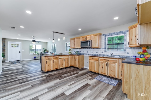 kitchen featuring dark wood-type flooring, light brown cabinets, kitchen peninsula, pendant lighting, and decorative backsplash