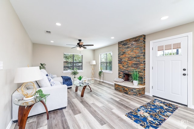 living room featuring ceiling fan, a fireplace, and light hardwood / wood-style flooring