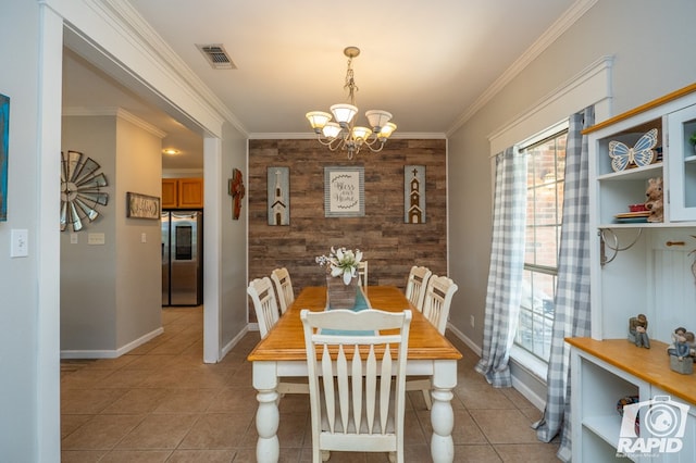 dining space with crown molding, wood walls, light tile patterned floors, and a notable chandelier