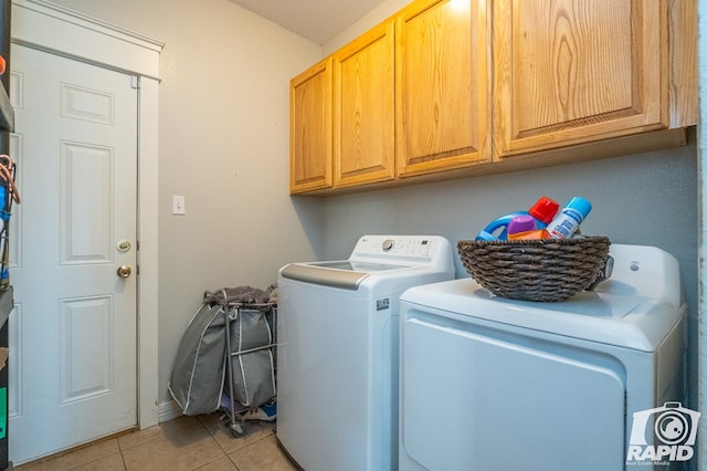 laundry area featuring light tile patterned floors, washer and clothes dryer, and cabinets