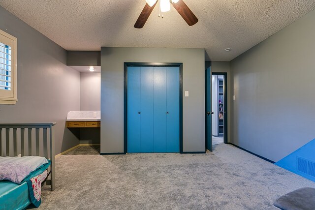 bedroom with ceiling fan, light colored carpet, a textured ceiling, and a closet