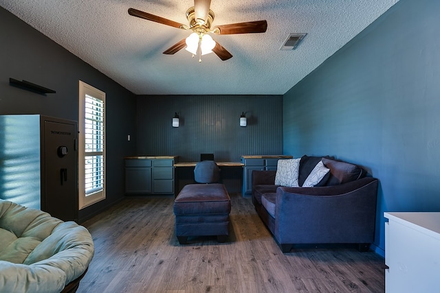 living room with dark hardwood / wood-style flooring, a textured ceiling, built in desk, and ceiling fan