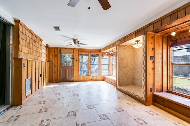 interior space featuring ceiling fan and wooden walls