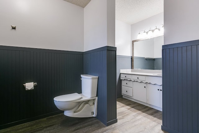 bathroom featuring vanity, wood-type flooring, toilet, and a textured ceiling